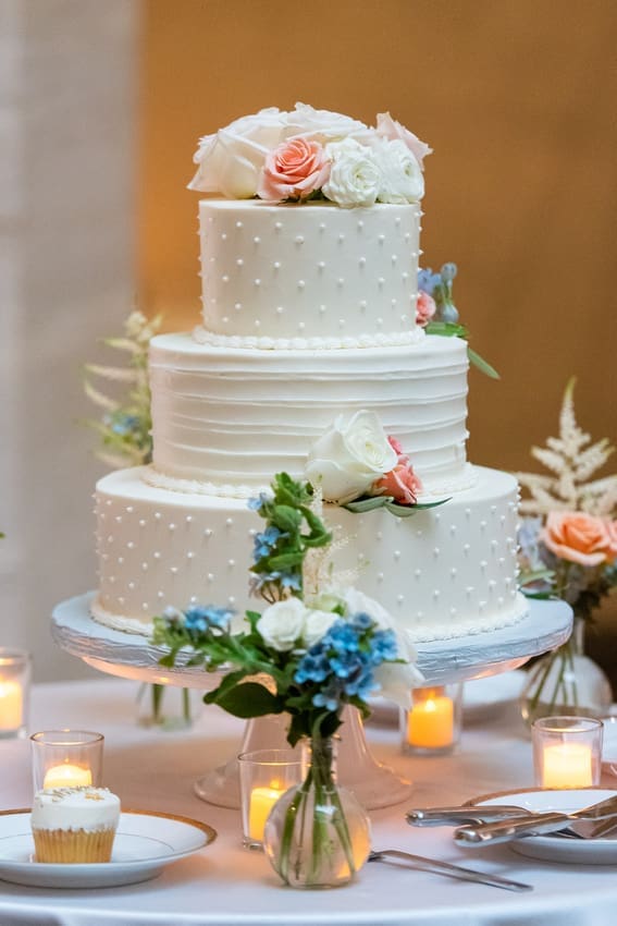 3 tiered white cake with dots and florals matching the bouquet and centerpieces