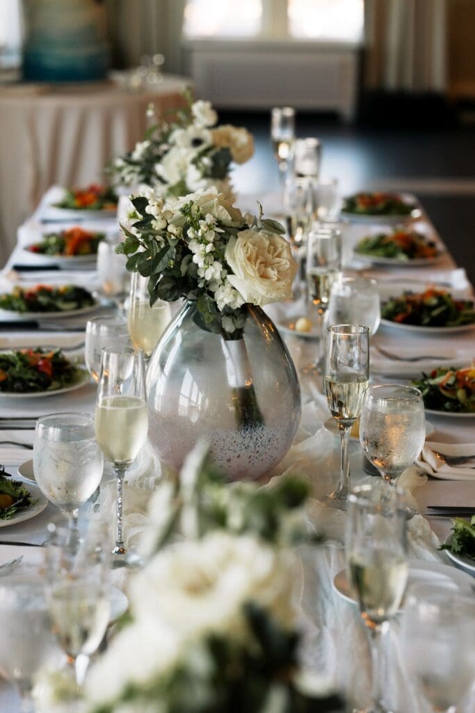 Head table with salads and bouquets in vases going down the table